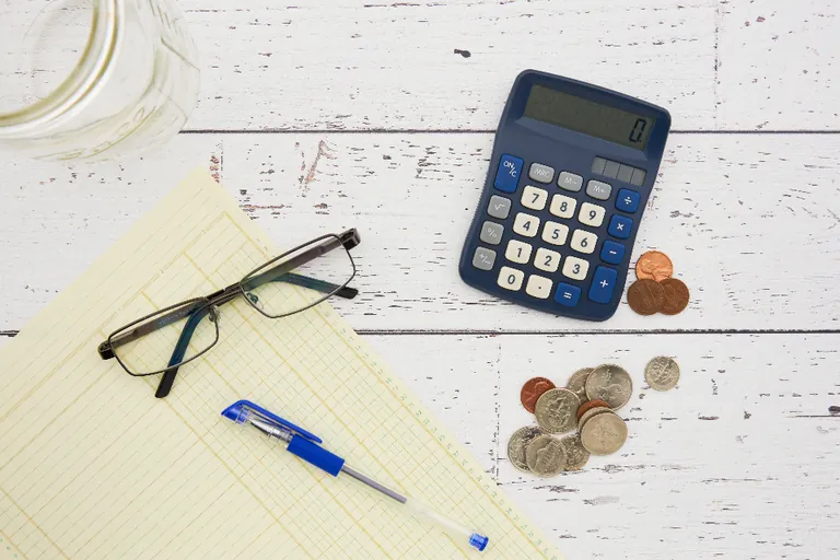 Calculator, notepad and coins on a desk — budgeting a pest control program in Lakeland FL